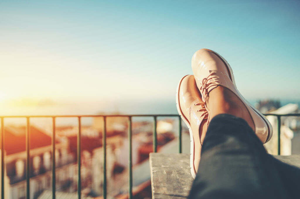 Close up of a woman sitting with their feet up on a balcony